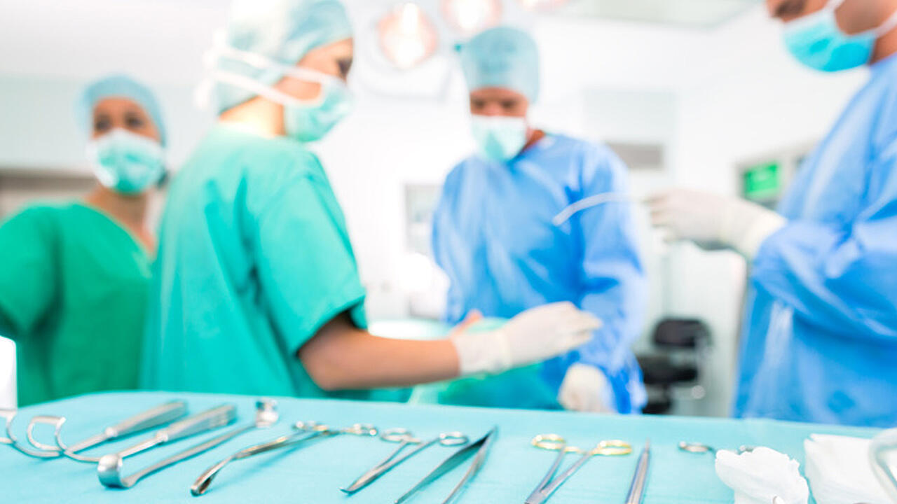 &Auml;rzte und Schwestern am Operationstisch, der sich im Vordergrund mit vielen Instrumenten darauf befindet 